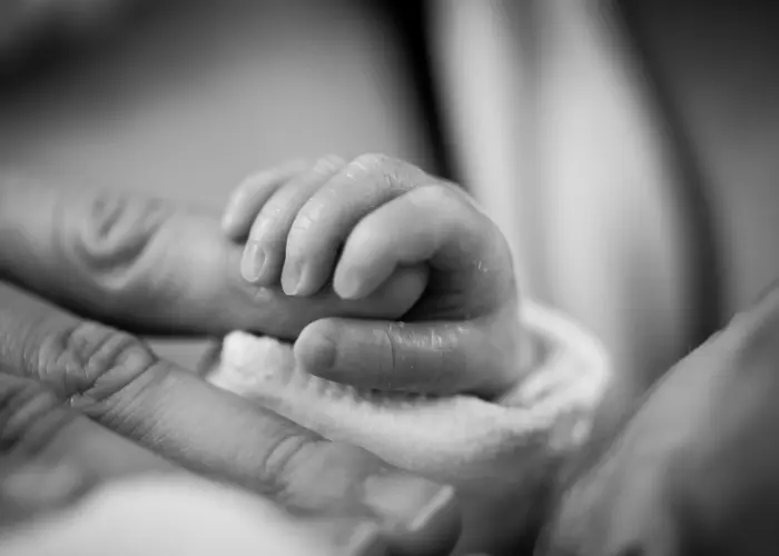 Newborn baby holding parent's finger – symbolic representation of Turkish citizenship by birth under jus sanguinis and jus soli principles.